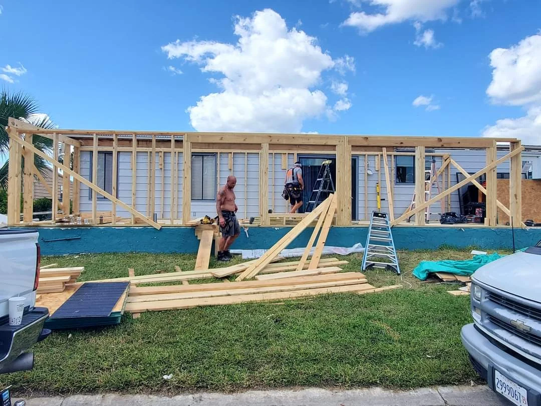 Exterior addition in progress, with timber wall framing and construction materials under a blue sky.