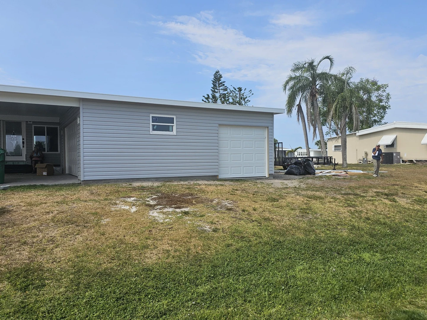 Garage exterior with a white overhead door, a stickered window and materials nearby during work.
