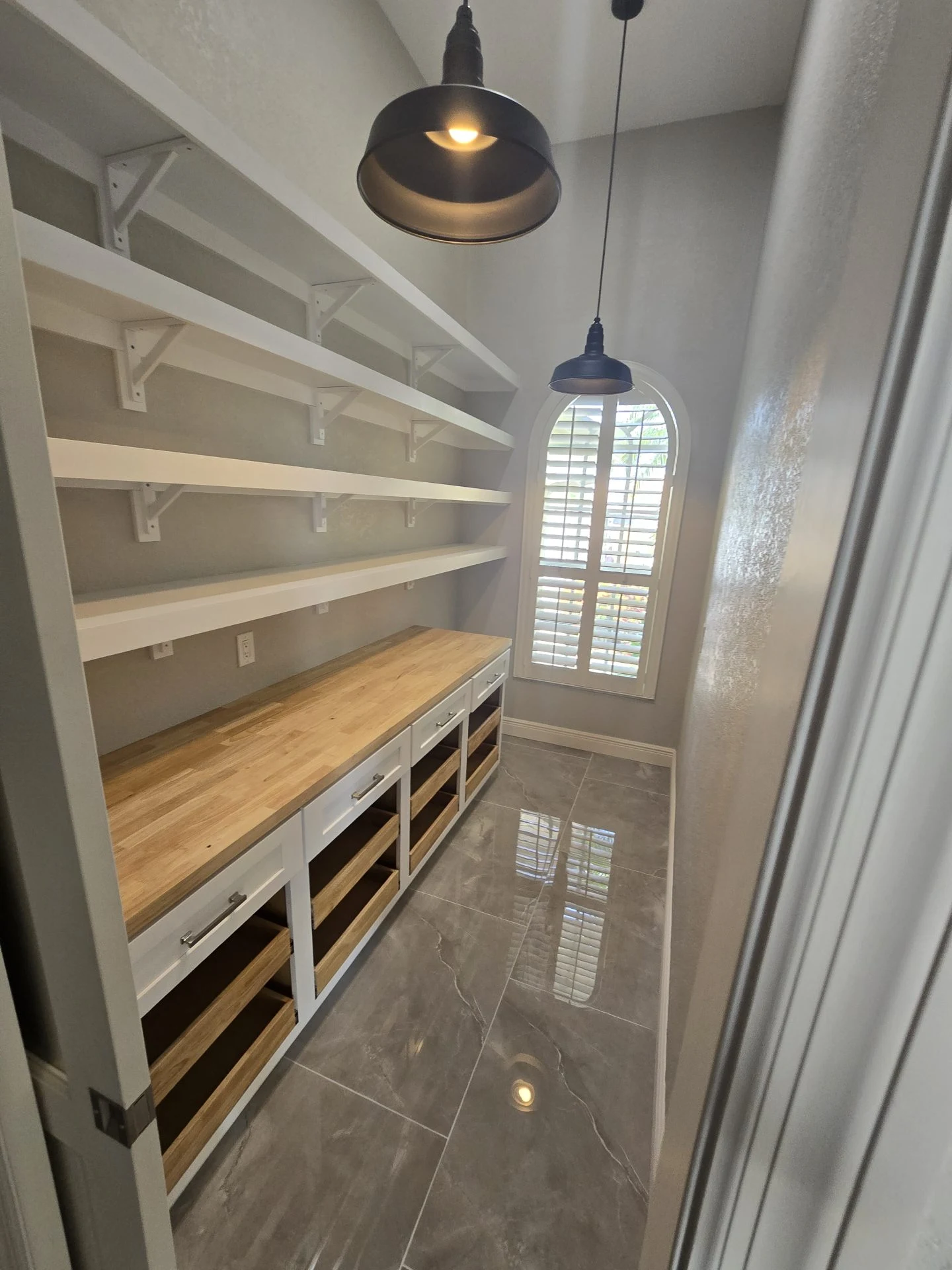 Walk-in pantry with open shelves, a wood countertop and pendant lighting.